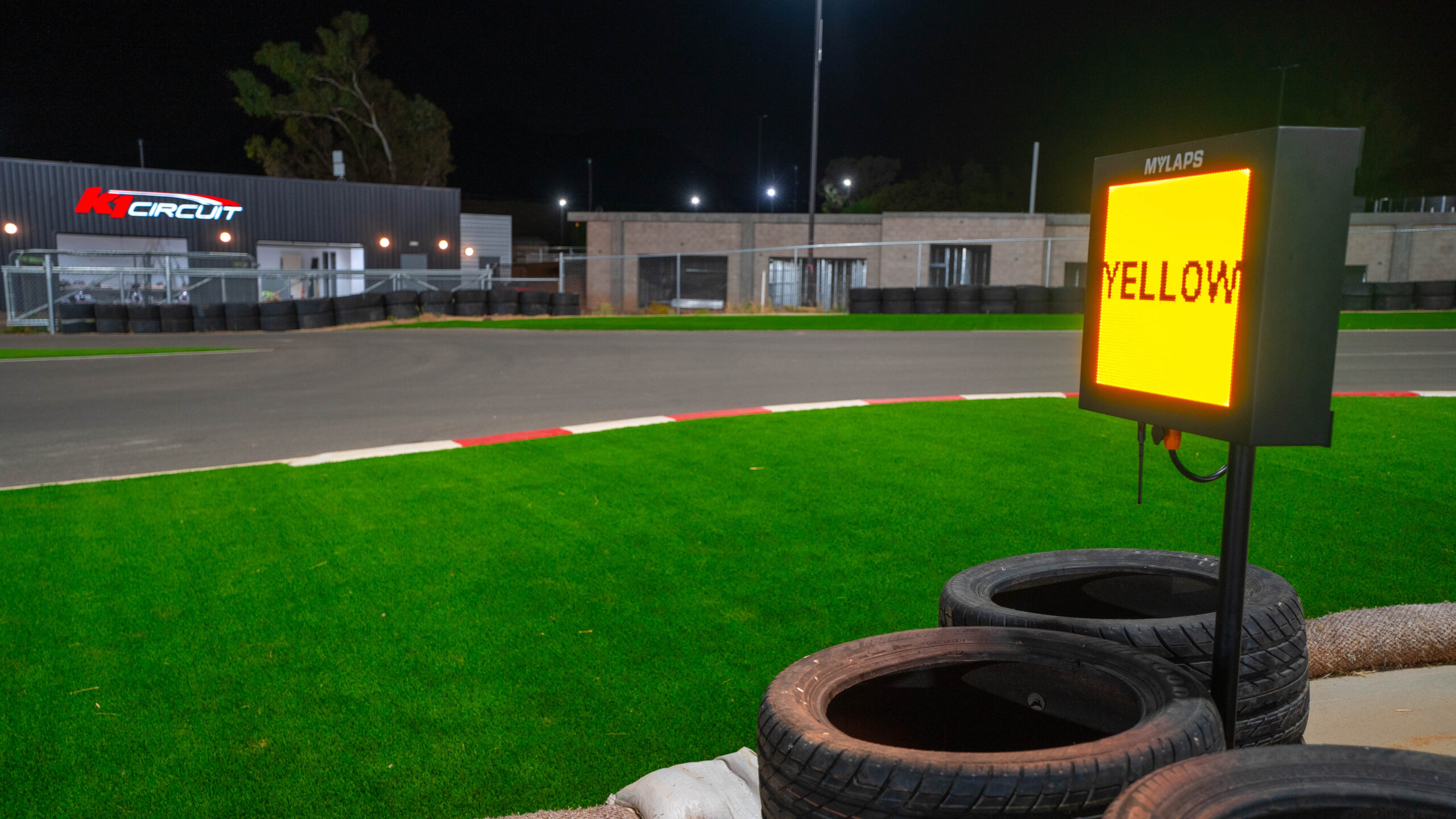 a flag panel lights up yellow at k1 circuit with the garages in the background