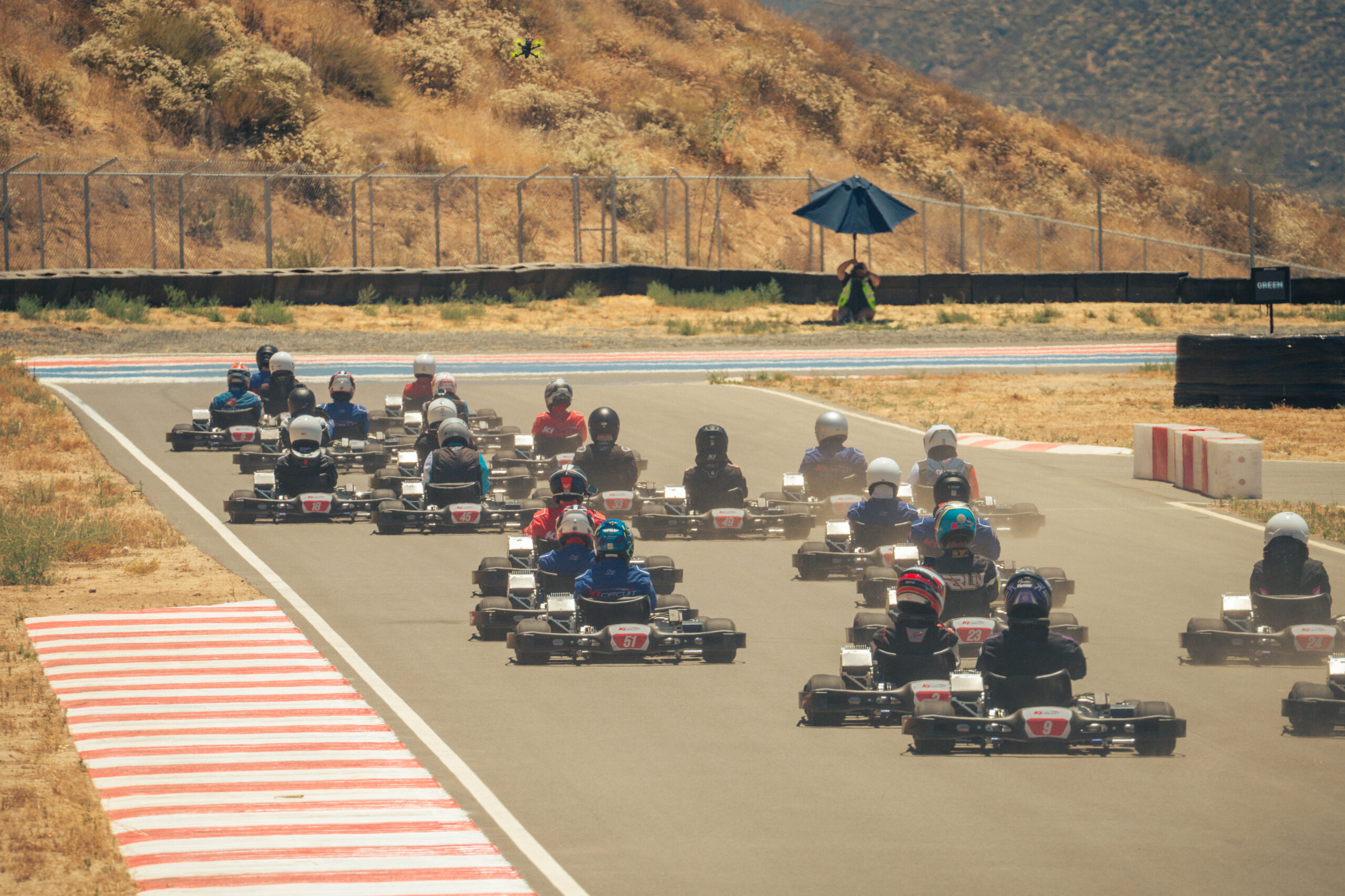 dozens of karts race side by side down the top straight at k1 circuit